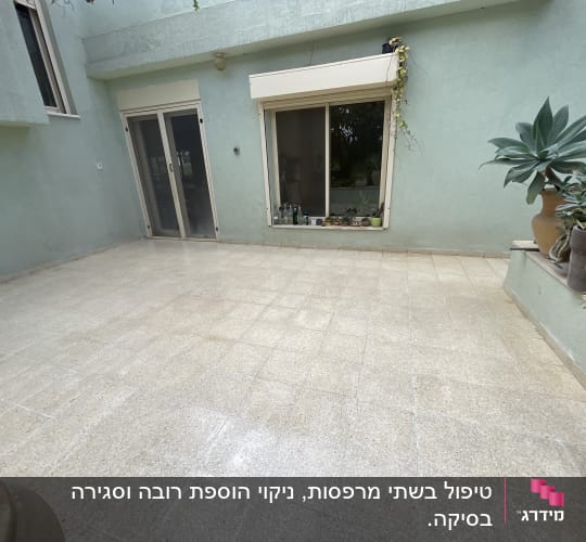 חצר מרוצפת עם דלתות זכוכית וצמחייה מסביב